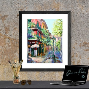 Print view of a vibrant New Orleans French Quarter scene, Pirates Alley is depicted with colorful buildings adorned with balconies and lush greenery.