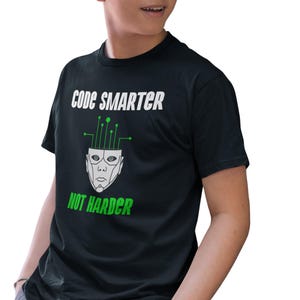 Könnte beinhalten: Ein schwarzes T-Shirt mit einer weißen Grafik, auf der "Code Smarter Not Harder" steht. Die Grafik enthält auch ein stilisiertes Bild eines menschlichen Kopfes mit Leiterplattenlinien, die aus dem oberen Teil herausragen.
