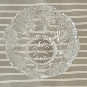 Peut inclure: Un bol en verre taill&eacute; transparent avec un bord festonn&eacute; et des motifs complexes de feuilles et d'&eacute;clats d'&eacute;toiles. Le bol rond semble &ecirc;tre en cristal. Le design sym&eacute;trique est adapt&eacute; au service ou &agrave; l'exposition. Diam&egrave;tre: environ 15 cm.