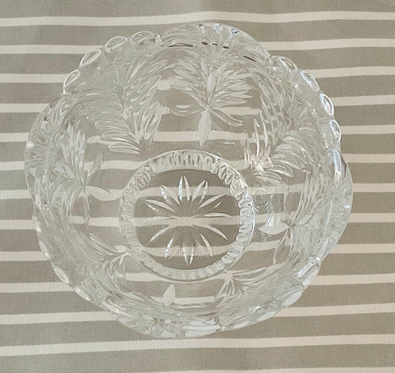 Peut inclure: Un bol en verre taill&eacute; transparent avec un bord festonn&eacute; et des motifs complexes de feuilles et d'&eacute;clats d'&eacute;toiles. Le bol rond semble &ecirc;tre en cristal. Le design sym&eacute;trique est adapt&eacute; au service ou &agrave; l'exposition. Diam&egrave;tre: environ 15 cm.