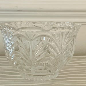Peut inclure: Bol en verre transparent avec un bord festonn&eacute; et un motif grav&eacute; d&eacute;taill&eacute;. Le bol a une forme arrondie et repose sur une petite base circulaire. Le motif grav&eacute; pr&eacute;sente un motif r&eacute;p&eacute;titif en forme de feuille, cr&eacute;ant un aspect textur&eacute;.