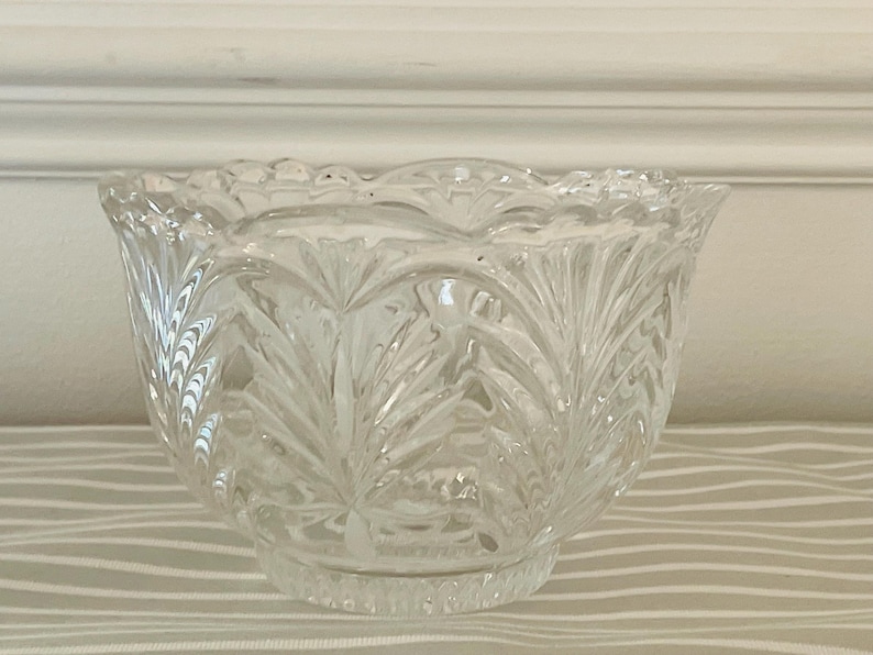Peut inclure: Bol en verre transparent avec un bord festonn&eacute; et un motif grav&eacute; d&eacute;taill&eacute;. Le bol a une forme arrondie et repose sur une petite base circulaire. Le motif grav&eacute; pr&eacute;sente un motif r&eacute;p&eacute;titif en forme de feuille, cr&eacute;ant un aspect textur&eacute;.