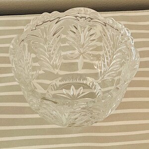 Peut inclure: Un bol en verre transparent et d&eacute;coratif avec un bord festonn&eacute;. Le bol pr&eacute;sente un motif de feuilles d&eacute;taill&eacute; grav&eacute; dans le verre. Le bol est rond et repose sur une surface ray&eacute;e. Id&eacute;al pour servir ou exposer.