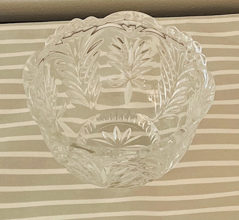 Peut inclure: Un bol en verre transparent et d&eacute;coratif avec un bord festonn&eacute;. Le bol pr&eacute;sente un motif de feuilles d&eacute;taill&eacute; grav&eacute; dans le verre. Le bol est rond et repose sur une surface ray&eacute;e. Id&eacute;al pour servir ou exposer.