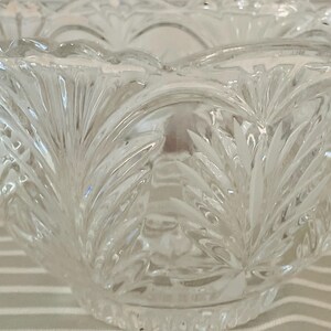 Peut inclure: Un bol en verre taill&eacute; transparent avec un bord festonn&eacute; et un motif de feuilles d&eacute;taill&eacute; et r&eacute;p&eacute;t&eacute;. Le motif du bol pr&eacute;sente des feuilles pointues verticales, cr&eacute;ant une surface textur&eacute;e. Le bol est probablement utilis&eacute; pour servir ou exposer.