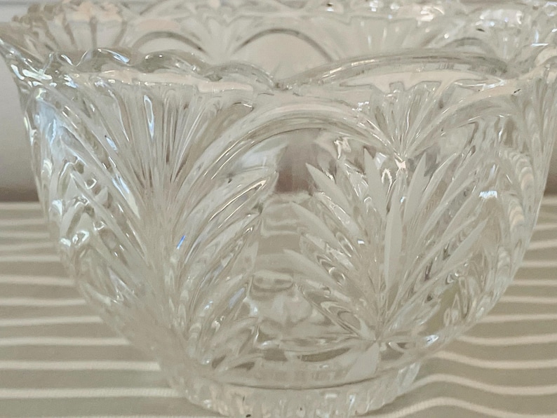 Peut inclure: Un bol en verre taill&eacute; transparent avec un bord festonn&eacute; et un motif de feuilles d&eacute;taill&eacute; et r&eacute;p&eacute;t&eacute;. Le motif du bol pr&eacute;sente des feuilles pointues verticales, cr&eacute;ant une surface textur&eacute;e. Le bol est probablement utilis&eacute; pour servir ou exposer.