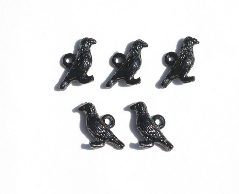 May include: Five black crow charms with a shiny finish. Each charm has a loop for attaching to a necklace, bracelet, or other jewellery.