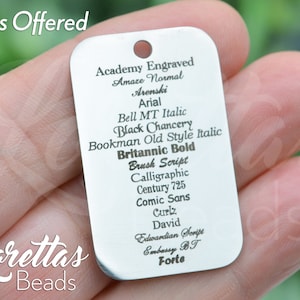 May include: A silver metal tag with a list of fonts, including Academy Engraved, Amaze Normal, Arenski, Arial, Bell MT Italic, Black Chancery, Bookman Old Style Italic, Britannic Bold, Brush Script, Calligraphic, Century 725, Comic Sans, Curlz, David, Edwardian Script, Embassy BT, and Forte.