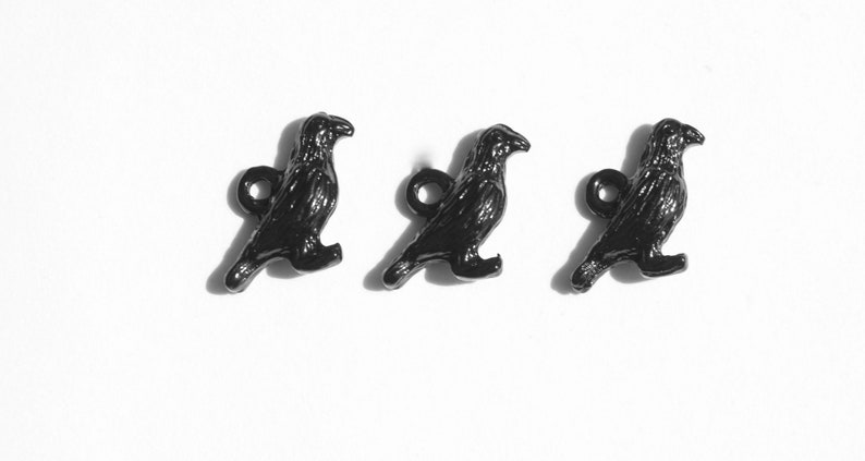 May include: Three black crow buttons with a shiny finish. Each button features a detailed crow design with a small loop for attaching.
