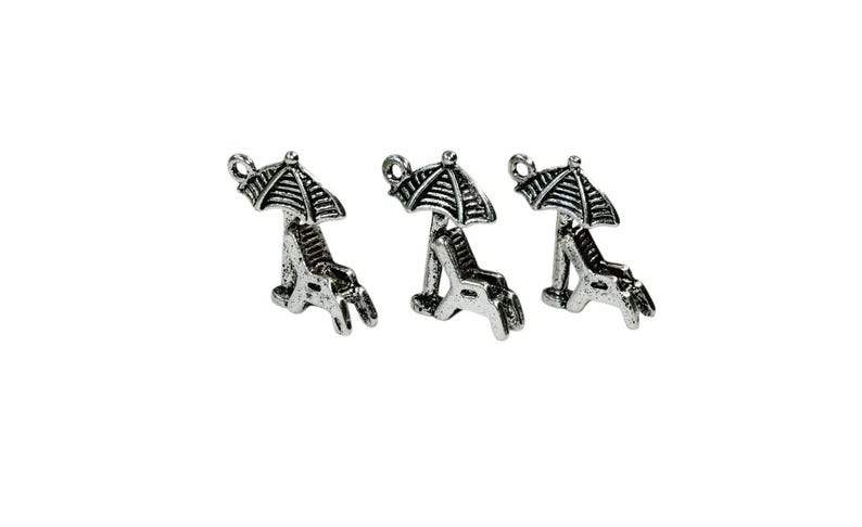May include: Three silver-toned charms in the shape of a beach chair with an umbrella. The charms are perfect for adding a summery touch to jewelry or crafts.