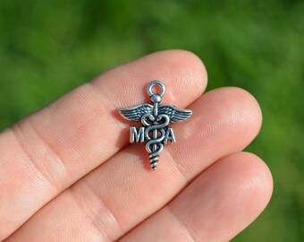 May include: Silver charm with a medical caduceus symbol and the letters "MDA" on a finger.