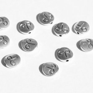 May include: Ten silver-toned metal beads with a raised Aries zodiac symbol on each bead. The beads have a hole for stringing.