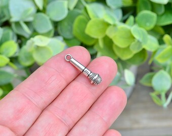 Op de afbeelding: Zilveren bedel in de vorm van een microfoon. De bedel heeft een lus aan de bovenkant om aan een armband of ketting te bevestigen.