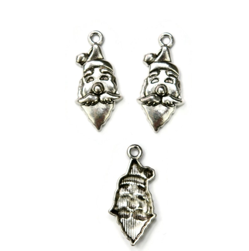 May include: Three silver charm pendants featuring a Santa Claus face. The charms are detailed with a white beard, red hat, and a smiling face.