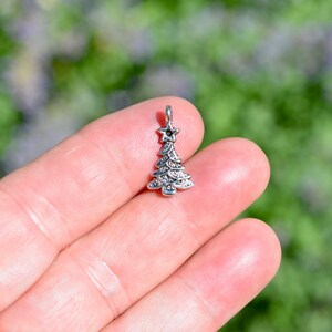 Puede incluir: Encanto de plata en forma de árbol de Navidad con una estrella en la parte superior.