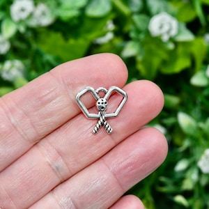 May include: Silver charm in the shape of two crossed lacrosse sticks with a ball in the centre.
