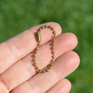 May include: A gold-toned metal key chain with a small, round link design.