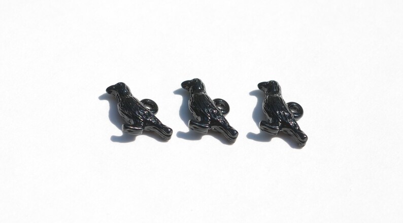 May include: Three black crow buttons with a shiny finish. Each button features a detailed crow design with a small loop at the top.