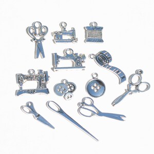 May include: A collection of silver-toned metal charms with sewing themes. The charms include sewing machines, scissors, spools of thread, buttons, and a measuring tape.