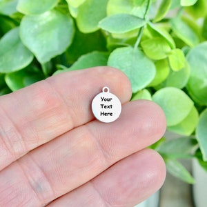 May include: A silver round charm with the text "Your Text Here" on it.