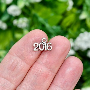 May include: Silver charm with the year 2016 printed on it.