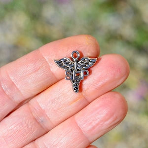 May include: Silver charm in the shape of a medical caduceus with the word "SLEEP" inscribed on it.