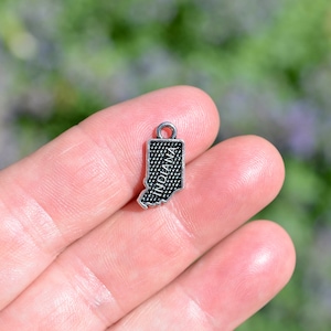 May include: Silver charm shaped like the state of Indiana with the word "INDIANA" inscribed on it.