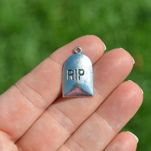 May include: Silver charm shaped like a tombstone with the word "RIP" engraved on it.