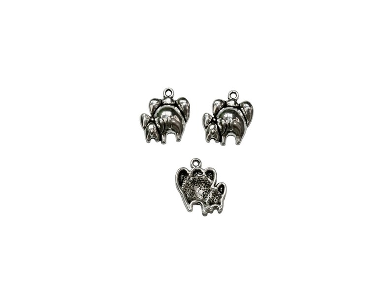 May include: Three silver charm pendants in the shape of elephants. The elephants are standing in a family group, with a larger elephant in the back and two smaller elephants in front.