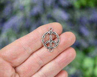 May include: A silver-coloured peace symbol charm with a circular wreath design. The peace sign is in the centre, with a floral accent. The charm has two loops for attaching to jewellery or other crafts.
