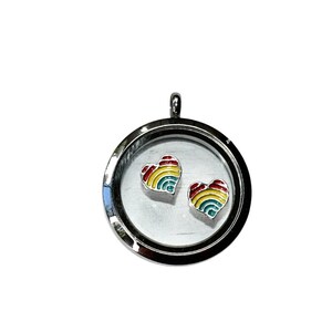 May include: A silver locket with a clear glass front, containing two heart-shaped charms. Each charm features a rainbow design with red, orange, yellow, green, and blue stripes. The locket has a loop at the top for a chain.