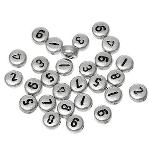 May include: A collection of silver-colored metal beads with black numbers printed on them. The numbers range from 1 to 9.