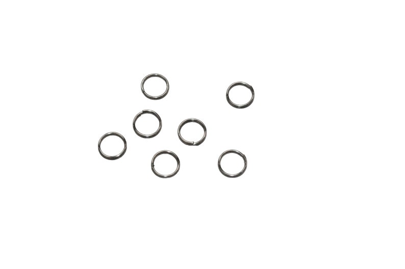 May include: A set of eight silver jump rings, scattered on a white background.