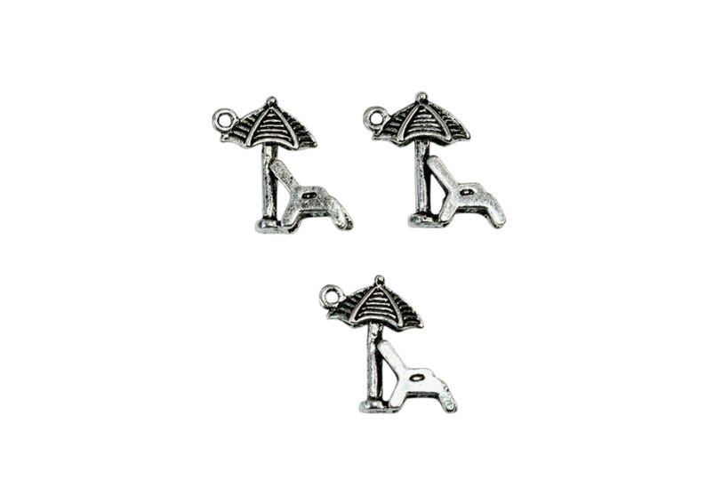 May include: Three silver charm pendants featuring a beach chair and umbrella design. The charms are perfect for adding a summery touch to jewelry.