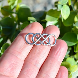 May include: Silver infinity symbol charm, a continuous loop representing eternity, for jewelry making.