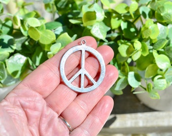 May include: A silver peace sign charm pendant. The charm is round and has a simple, classic design.