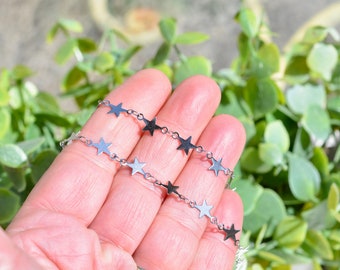 May include: A silver chain necklace with star-shaped charms. The chain is delicate and the stars are small.