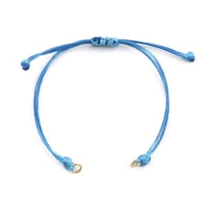May include: A blue adjustable bracelet with gold jump rings. The bracelet is made of thin cord and has a simple knot design.