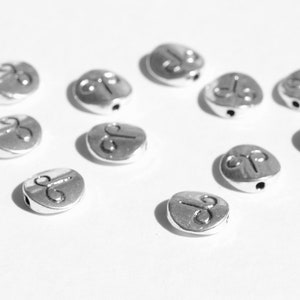 May include: A collection of silver metal beads with a symbol of a ram's head on each bead.
