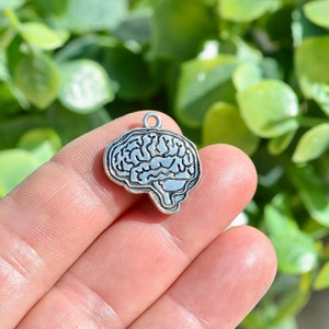 May include: Silver charm in the shape of a human brain. The charm is detailed and has a textured surface.