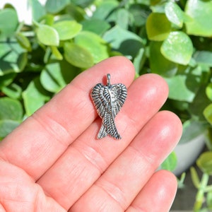 May include: Silver angel wing charm pendant with detailed feather design.