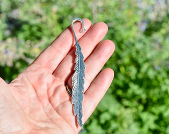 May include: Silver bookmark shaped like a feather with a loop at the top.