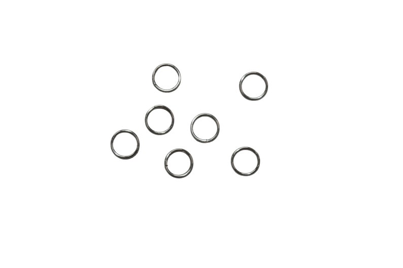 May include: A set of ten silver jump rings, scattered on a white background.