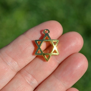 May include: A gold-colored metal charm in the shape of a Star of David.