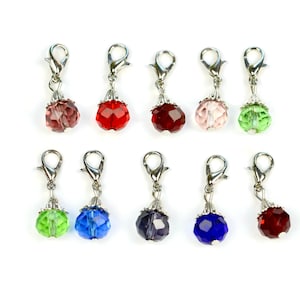 May include: Ten crystal bead charms with silver clasps. The beads are in various colors, including red, pink, green, blue, and purple.
