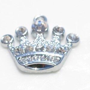 May include: Three silver crown charms with clear rhinestone accents.