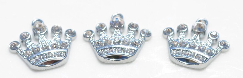 May include: Three silver crown charms with clear rhinestone accents.
