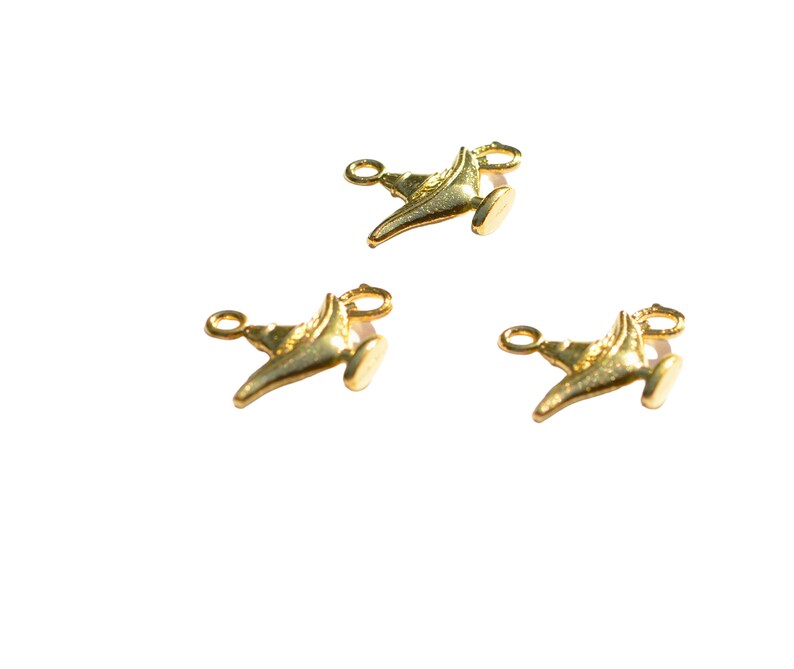 May include: Three gold-coloured genie lamp charms with a loop for attaching to a necklace or bracelet.