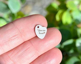 May include: A small silver heart charm with the words "You are loved" engraved on it.