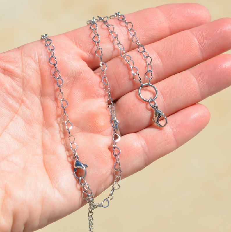 May include: A silver heart-shaped chain necklace with a lobster clasp closure.